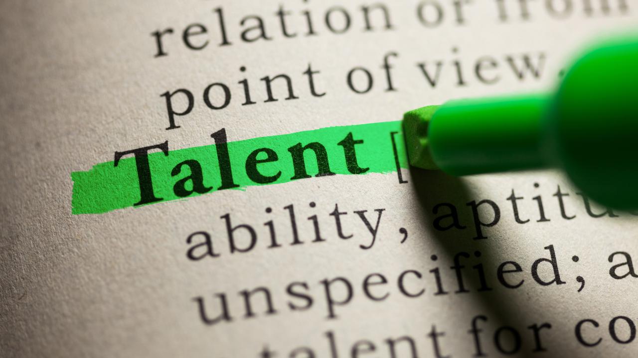 Destaque em marcador verde sobre a palavra Talent no dicionário, simbolizando por que talento não é suficiente para alcançar alta performance.