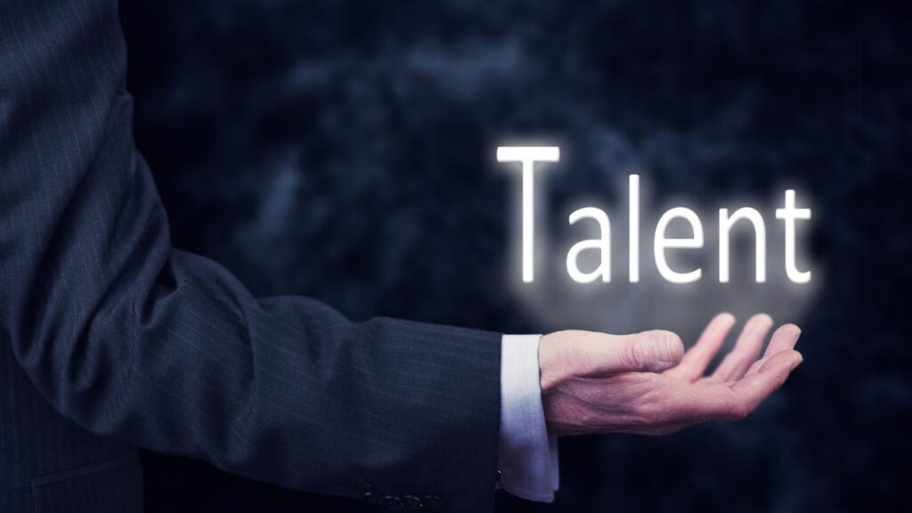 Mão estendida com a palavra “Talent” flutuando acima, simbolizando que talento sozinho não é suficiente para alcançar alta performance.