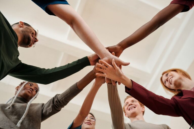 Grupo de pessoas unindo as mãos em círculo para motivação.